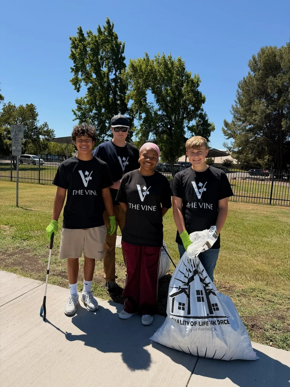 Four students with a litter grabber and a full City of Fairfield Quality of Life Task Force trash bag after a cleanup